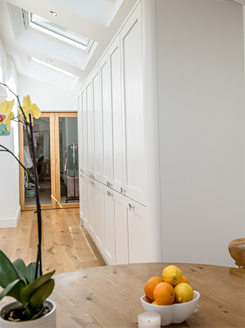 white kitchen storage area with wooden table